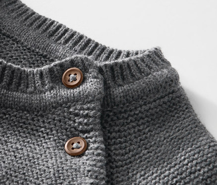 Kahverengi düğmeli çocuk örgü kazağının yakın çekimi.