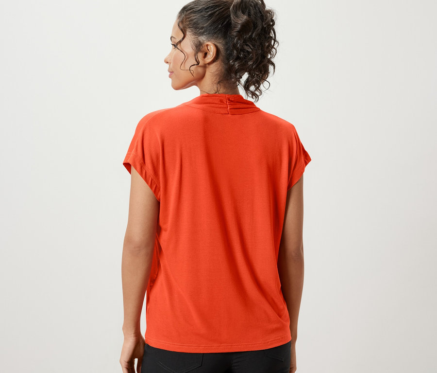 Turuncu V yakalı bluz ve siyah şort giyen bir kadının arka görünümü.