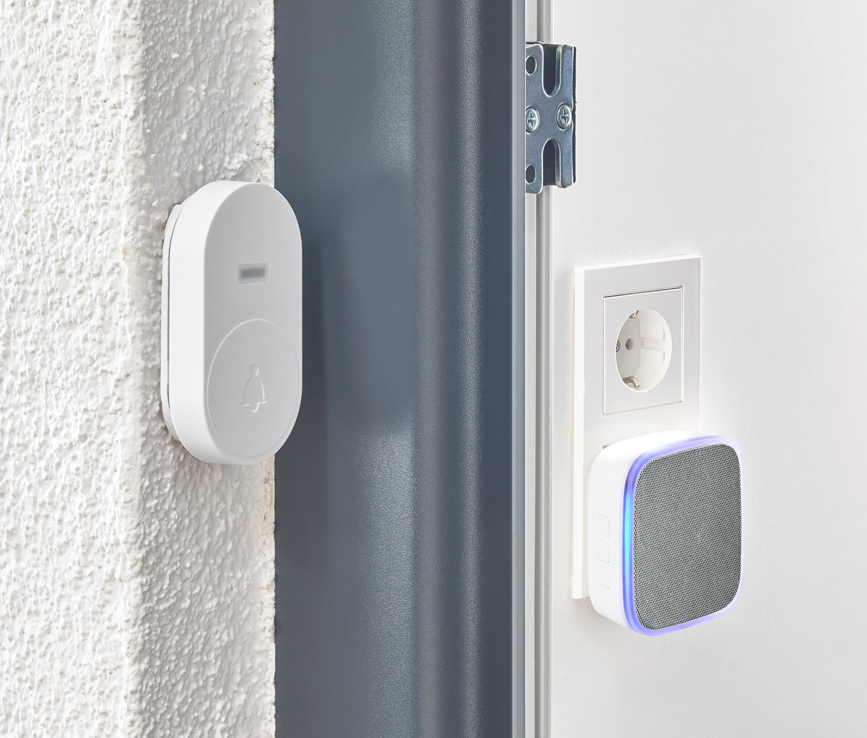 Beyaz bir kablosuz kapı zili seti, bir kapının yanındaki duvara monte edilmiştir.