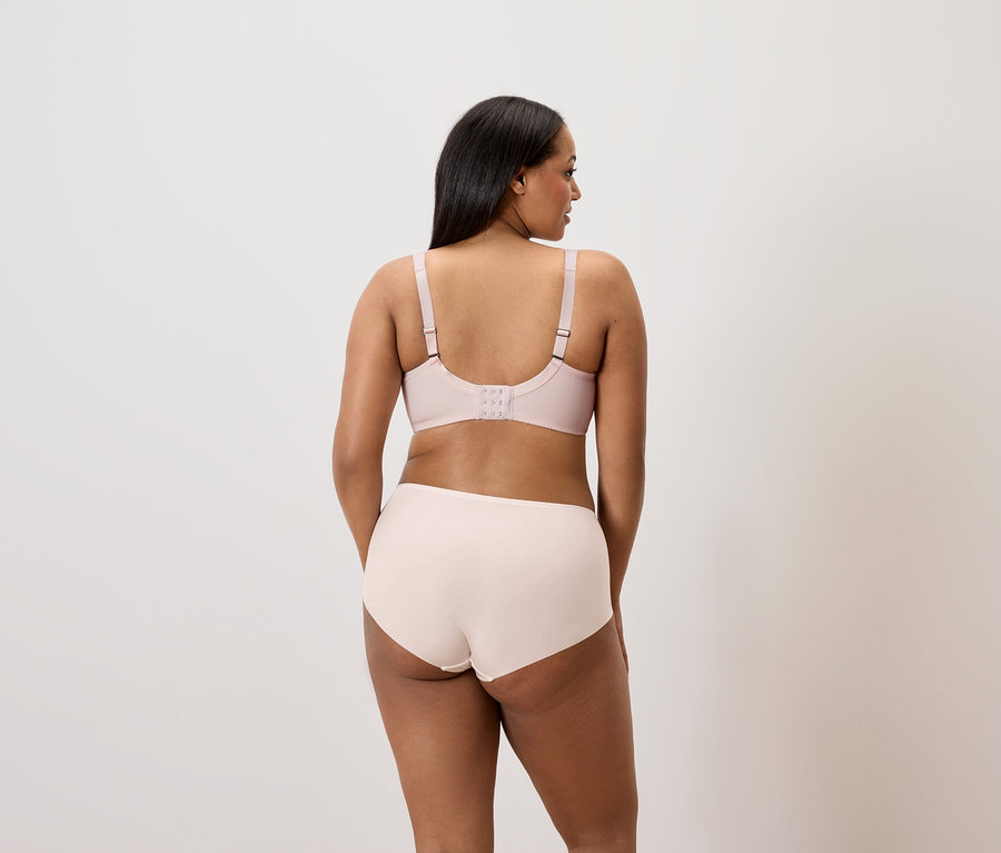Arka görünüm: Koyu saçlı bir kadın açık pembe bir sütyen ve külot giyiyor.