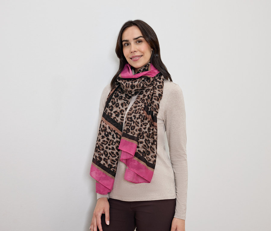 Koyu saçlı kadın, pembe detaylı leopar desenli bir eşarpla poz veriyor.