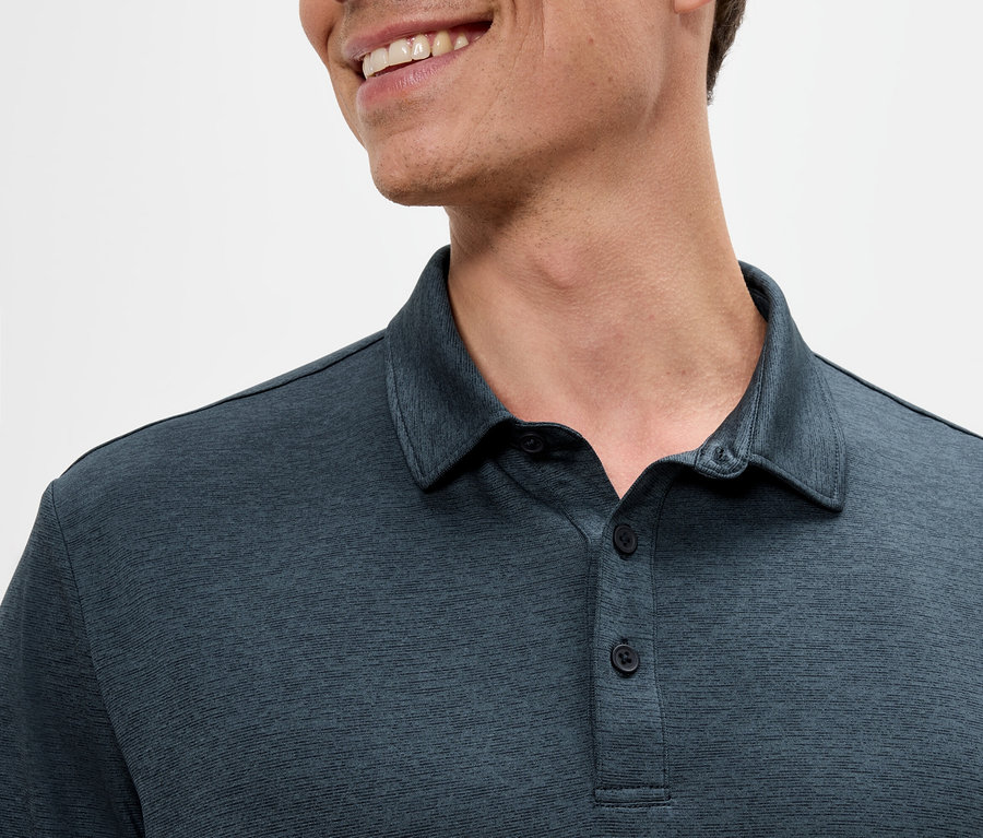 Yakalı lacivert bir polo tişört giyen ve gülümseyen bir adamın yakın çekimi.