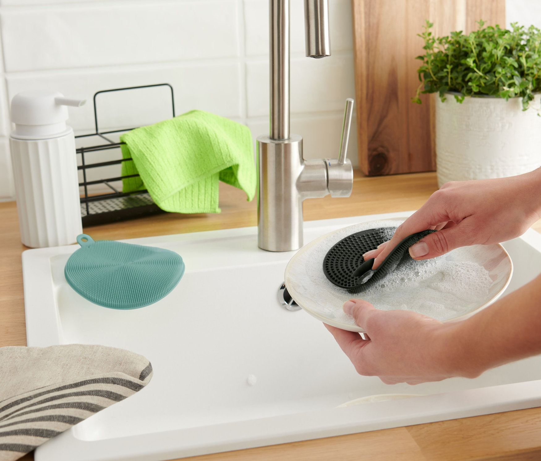 Kadın, 2 Adet Silikon Bulaşık Süngeri ile bir tabağı yıkıyor.