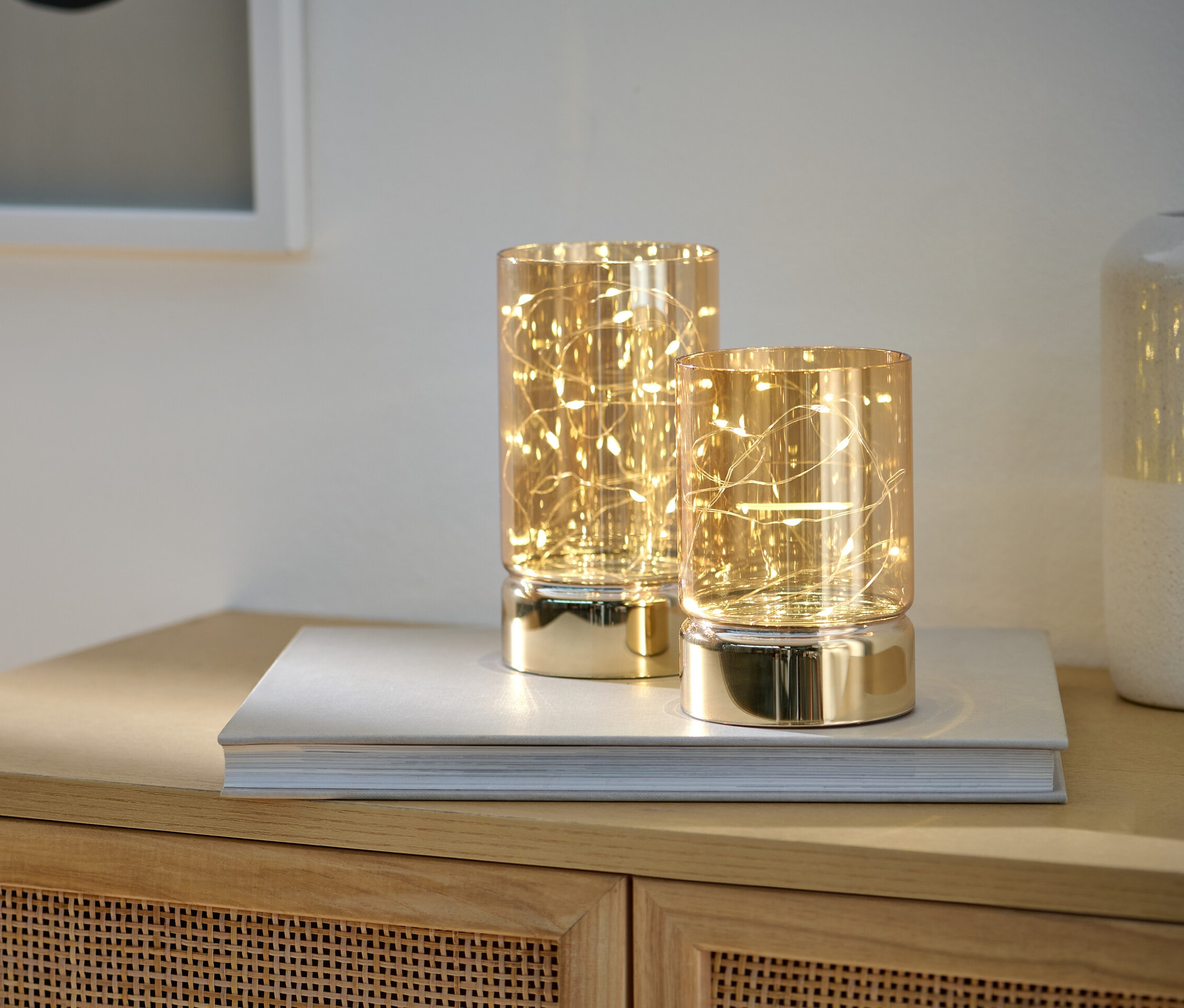 İki adet LED cam mumluk bir dolabın üzerindeki kitabın üstünde duruyor.