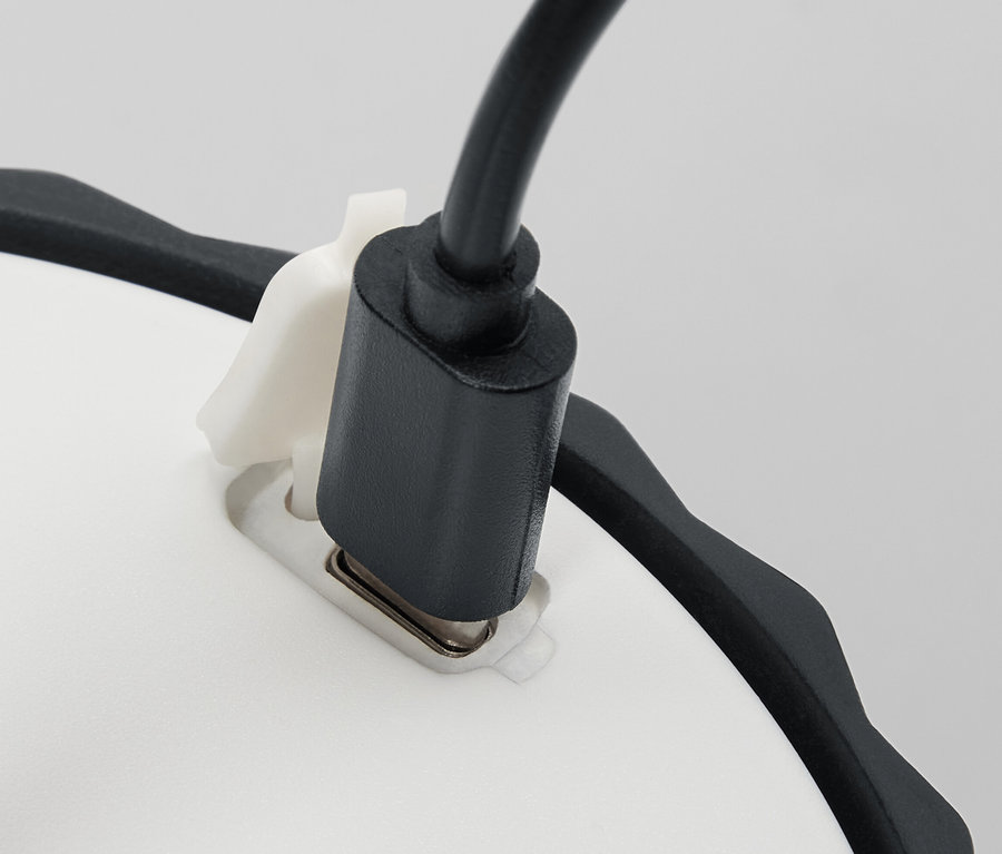 Beyaz tabana takılı siyah güç kablosuna sahip Küçük bir LED Masa Lambası'nın ayrıntılı görünümü.