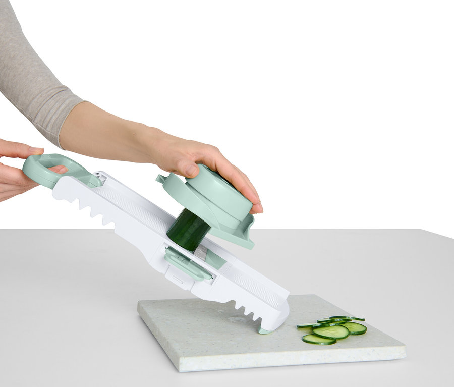 Kadın, sapı ve döner başlığı olan bir sebze dilimleyici ile salatalık doğruyor.