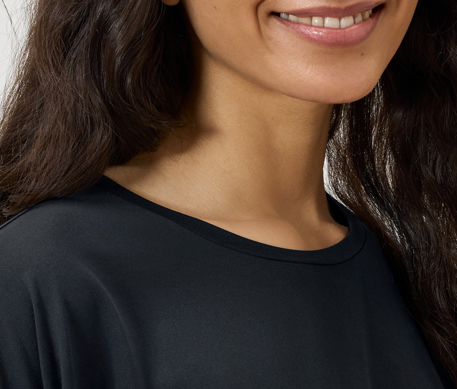 Koyu dalgalı saçlı ve siyah tişörtlü bir kadının yüzünün yakın çekimi.