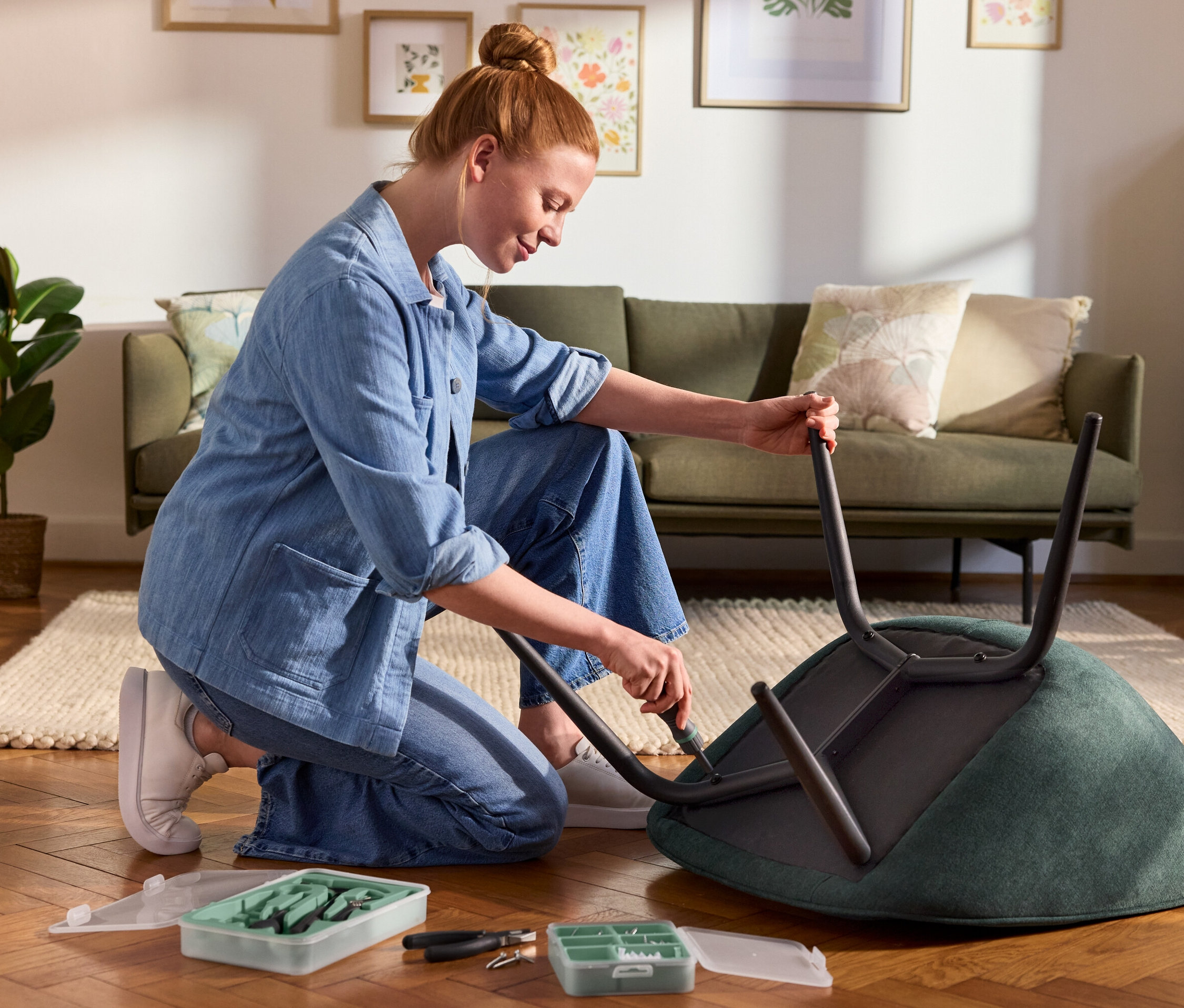 Bir kadın diz çökmüş halde bir alet setinden manyetik bir tornavida ile bir sandalyenin ayaklarını takıyor. Yakınlarda bir vida ve dübel seti var.