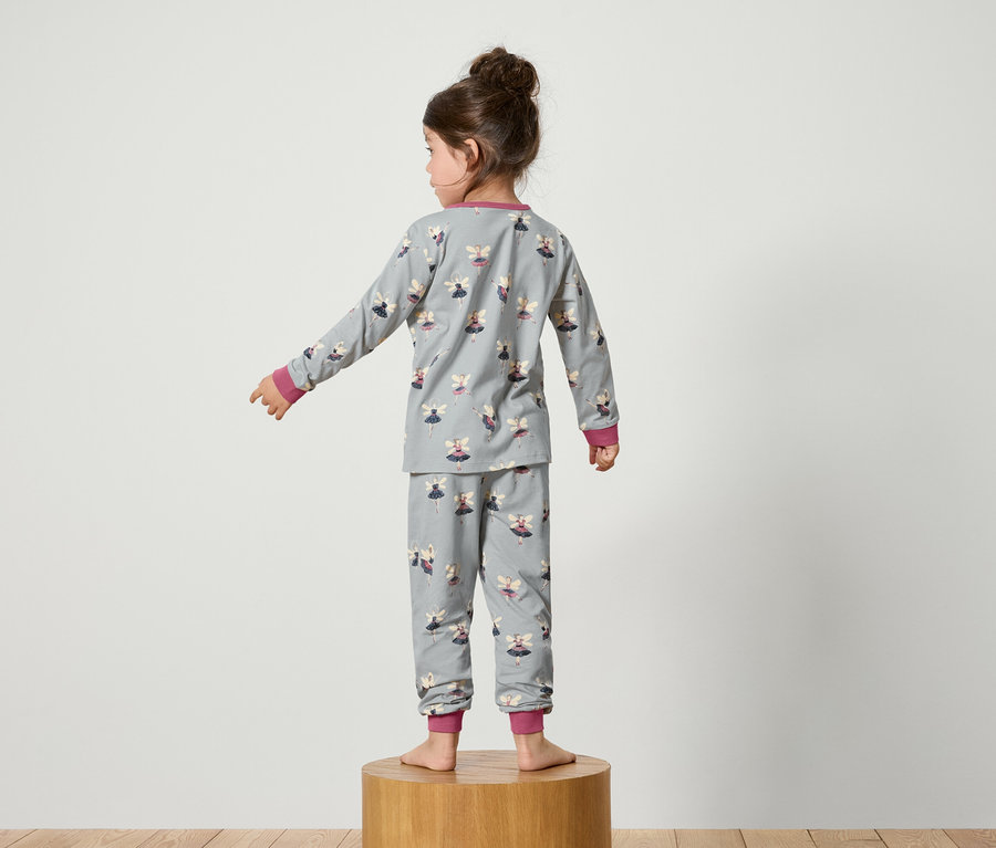Kız sırtı dönük duruyor, üzerinde peri baskılı gri bir pijama var.