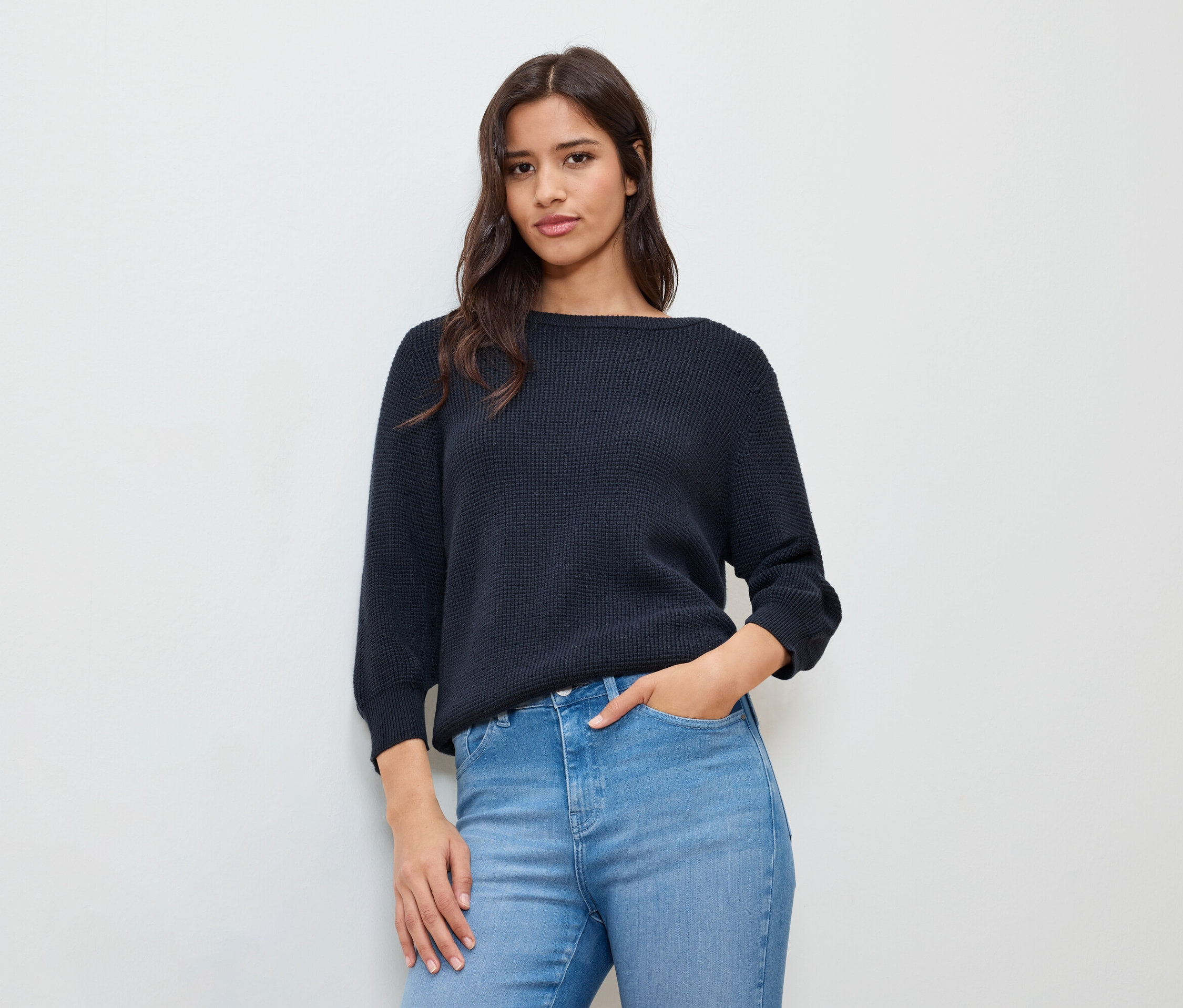 Eli cebinde, koyu mavi ince triko kazak giyen kadın.