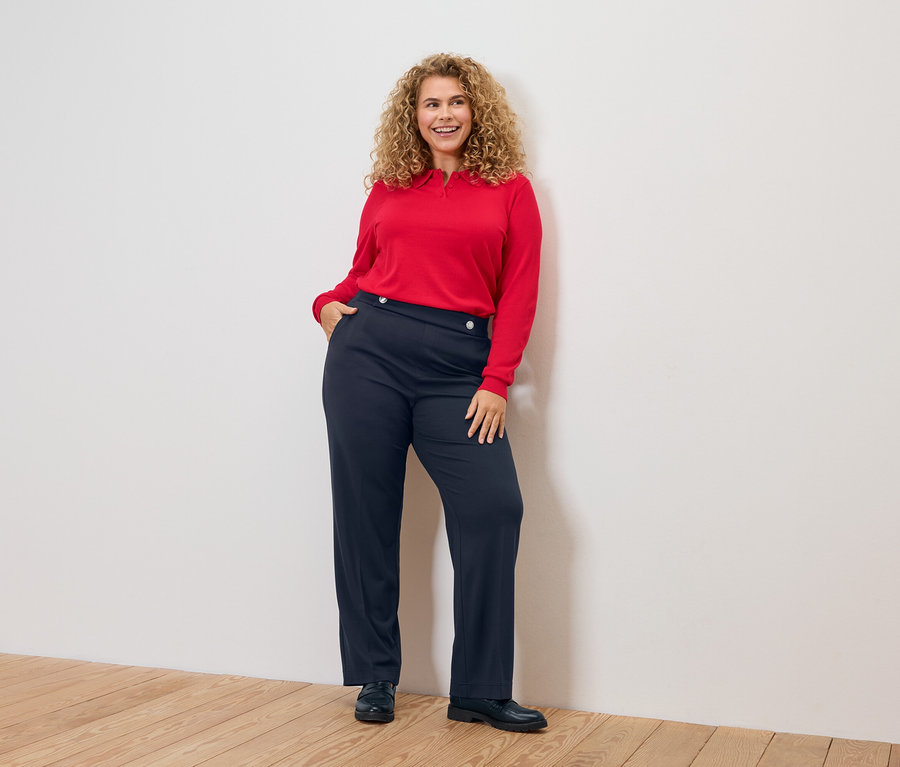 Kıvırcık saçlı, kırmızı bluzlu ve mavi pantolonlu kadın.