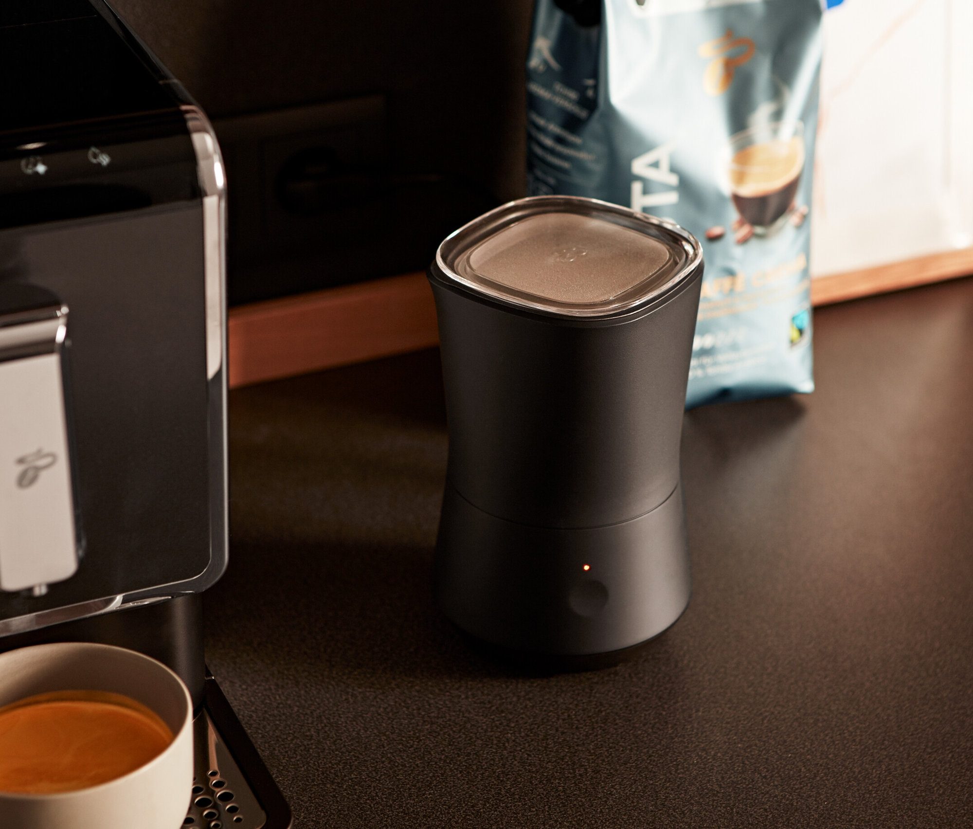 Kahve makinesi siyah elektrikli süt köpürtücünün yanında.