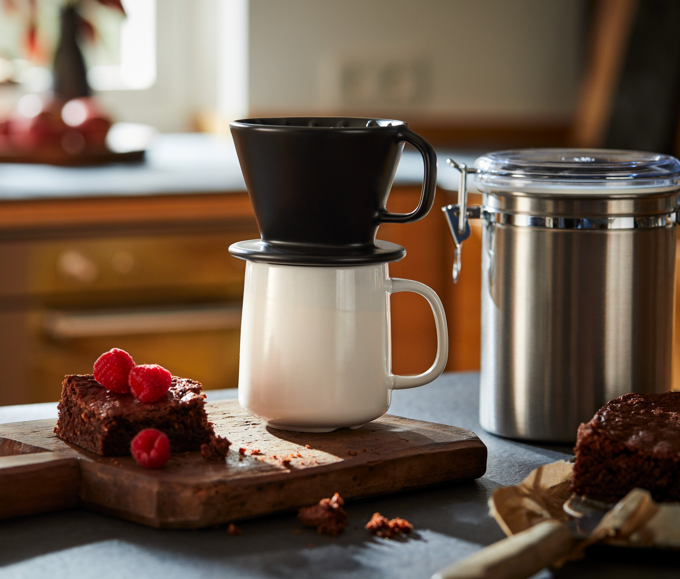 Siyah, No. 101 filtre kahve aparatı, ahşap bir kesme tahtası üzerinde ahududulu brownielerin yanında beyaz bir kupanın üzerinde duruyor.