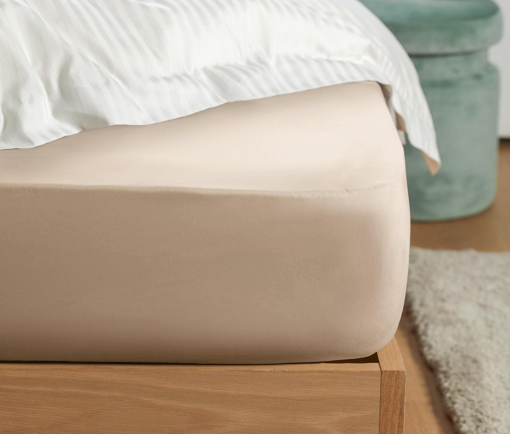 Bir yatak üzerinde bej renkli Jersey Lastikli Çarşafın yakın çekimi.