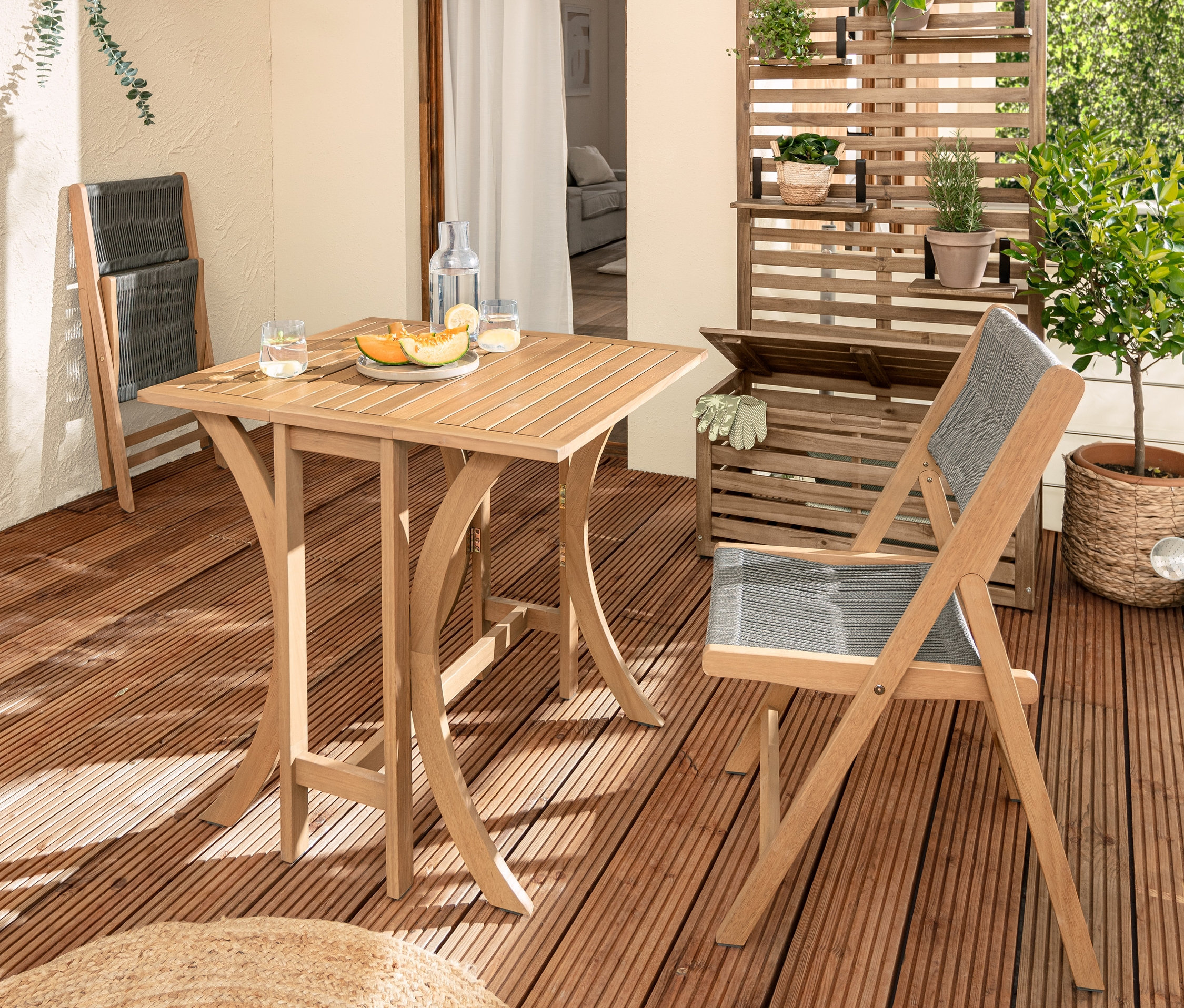 Bir balkonda kumaş örgülü katlanır balkon masa seti »Lenja« ile döşenmiş, saklama sandıklı »Lenja« balkon bankı ve balkon paravanı bulunmaktadır.