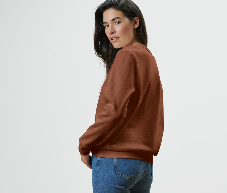 Omuz üzerinden bakan, sweatshirt ve kot pantolon giyen kadın.