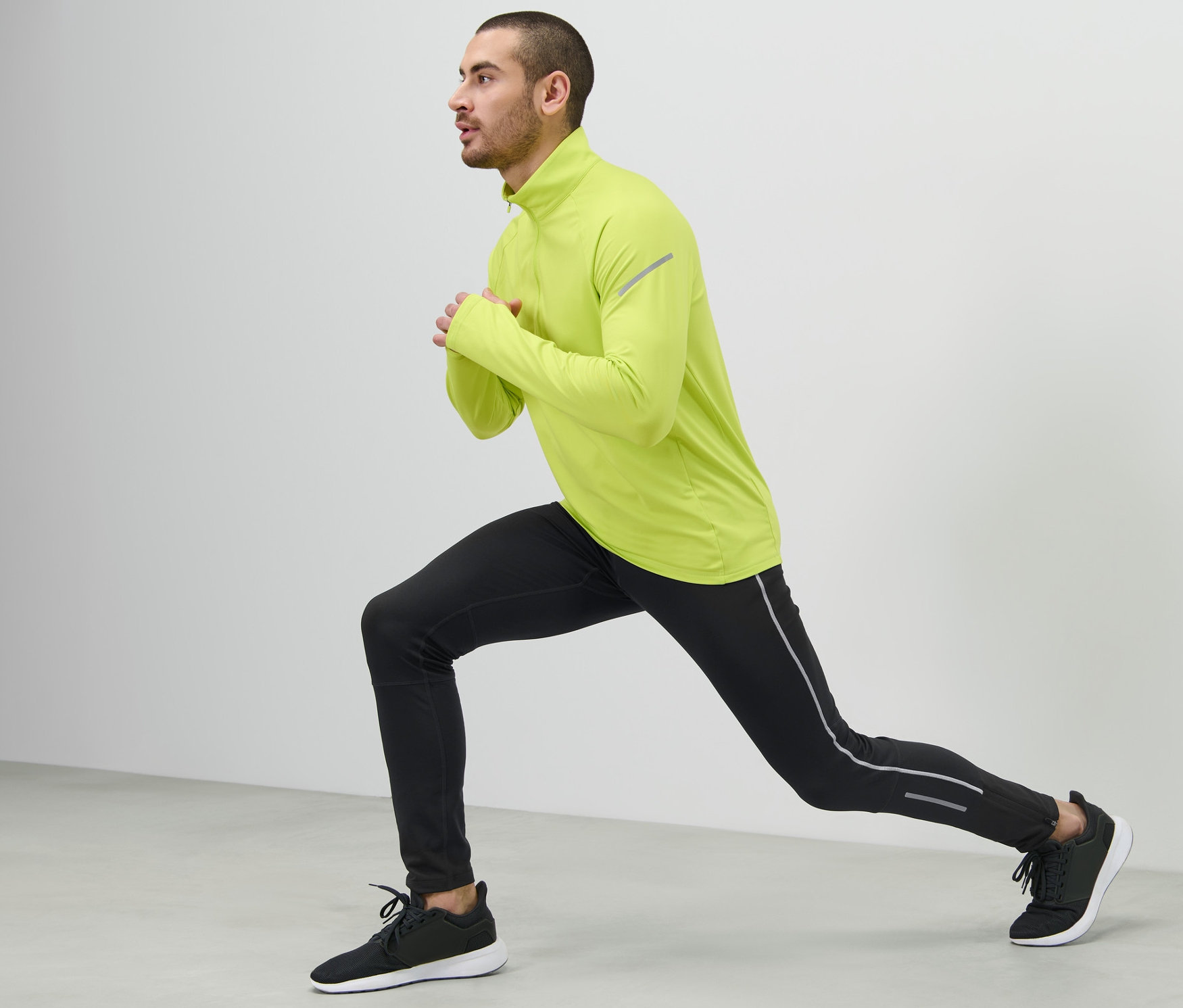 Yeşil üst ve siyah Termal Koşu Taytı giyen adam lunge yapıyor.
