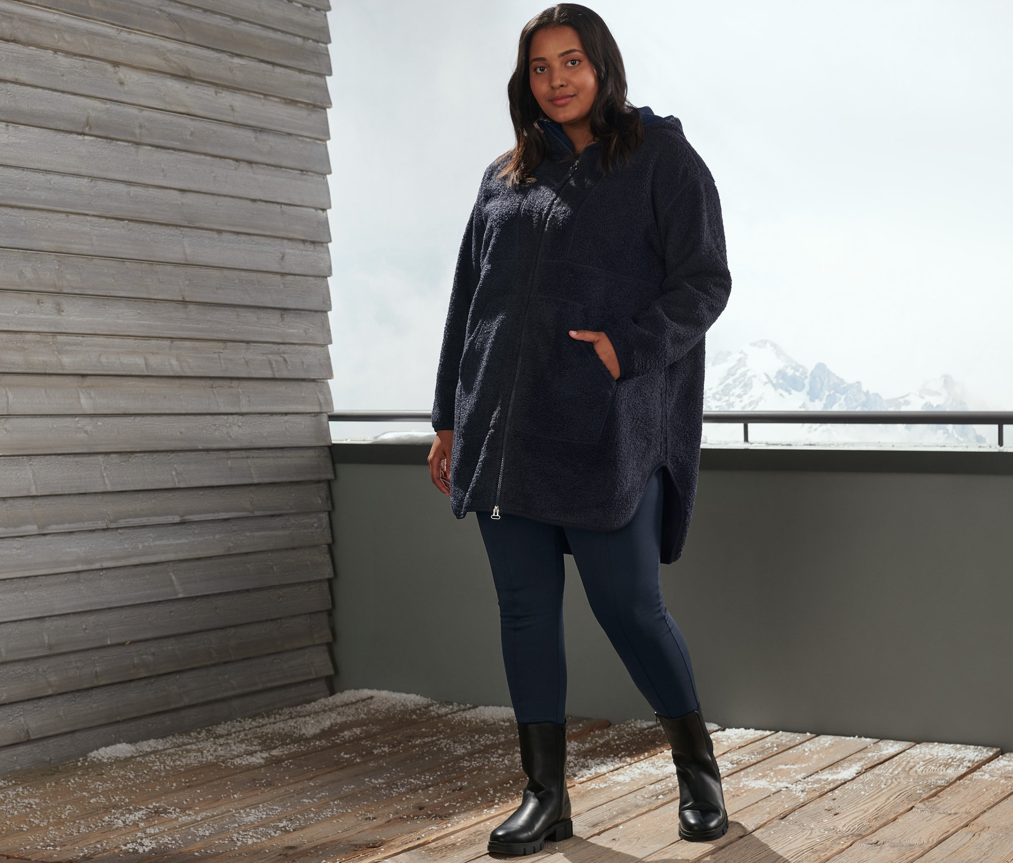 Kadın, lacivert oversize pelüş mont ve termal taytla dışarıda poz veriyor.