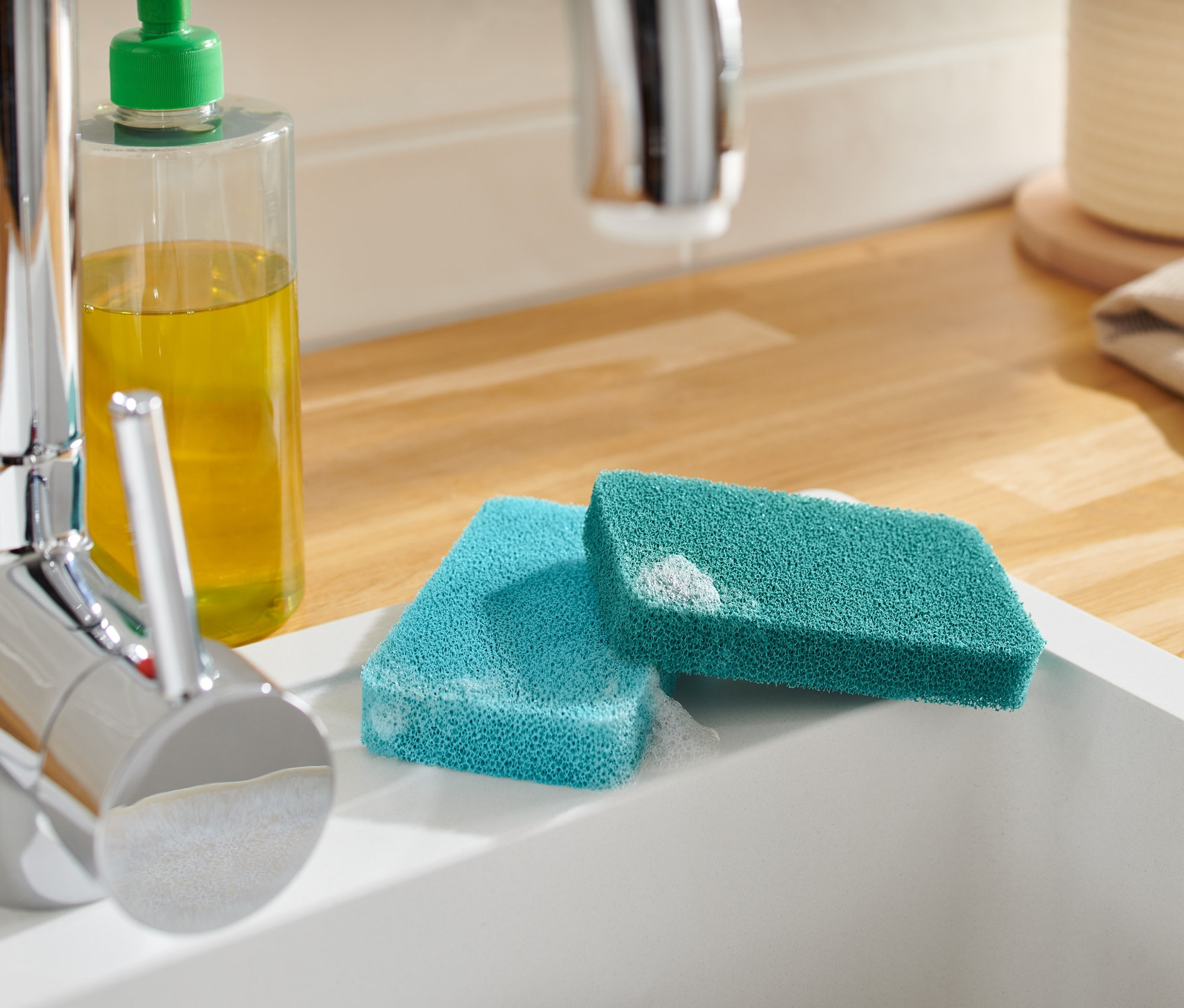 İki adet silikon sünger, lavabonun kenarında sabunun yanında duruyor.