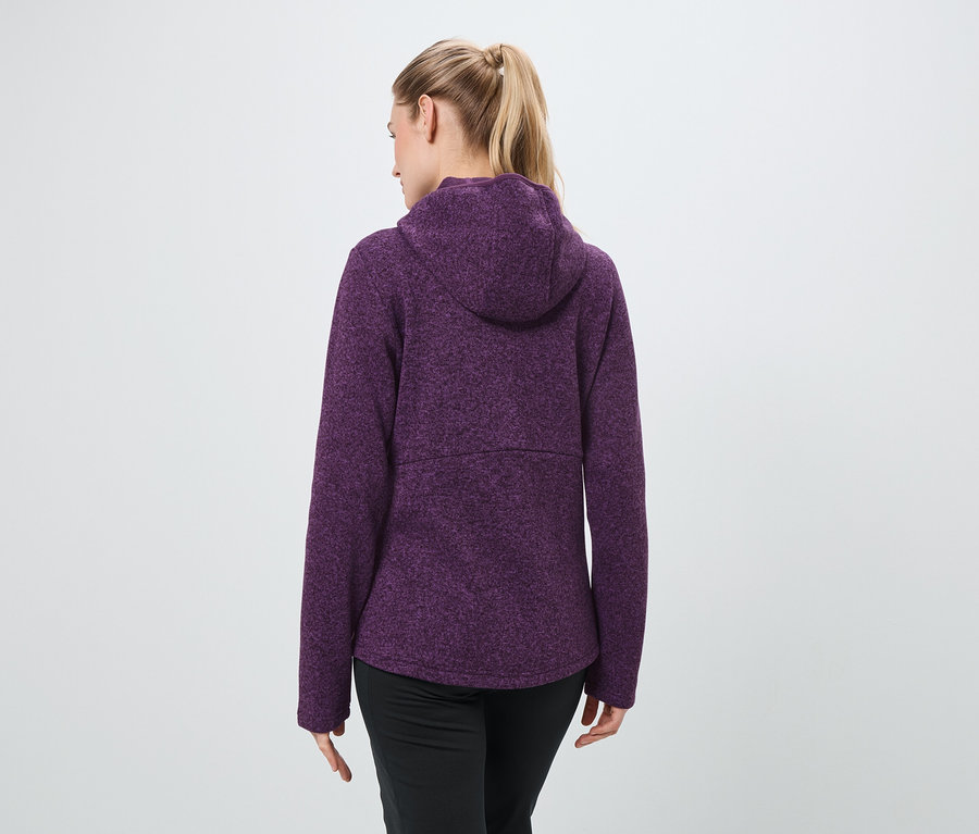 Arkadan, sarı saçları at kuyruğu yapılmış, mor kapüşonlu sweatshirt ve siyah pantolon giyen bir kadın görülüyor.