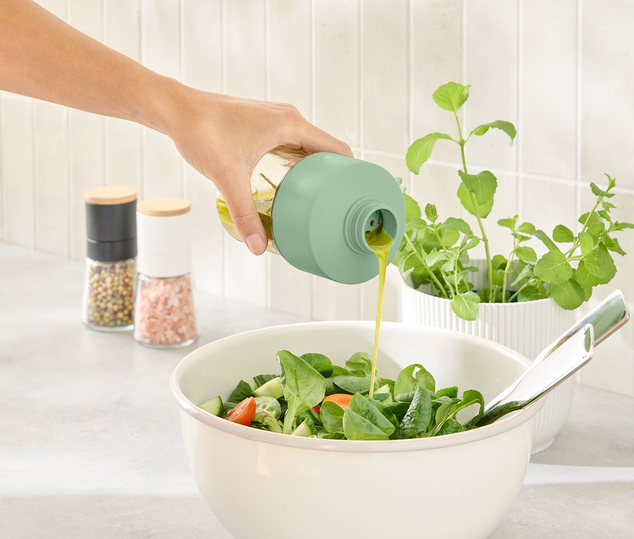 Bir el, sosluğu kullanarak salata kasesine sos döküyor.
