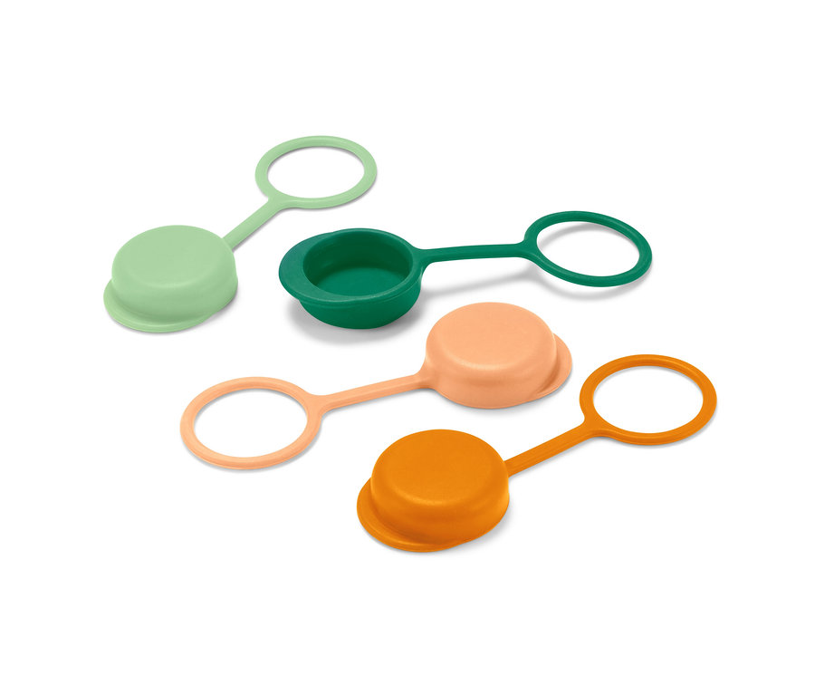 Yeşil, koyu yeşil, şeftali ve turuncu renklerde dört adet şişe kapağı beyaz bir yüzey üzerinde duruyor.