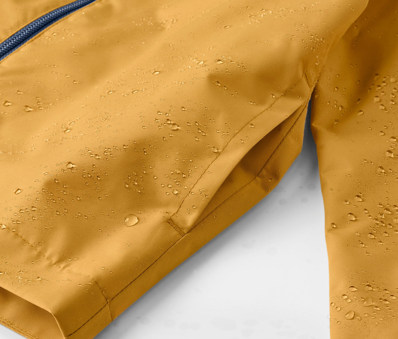 Su damlaları olan sarı renkli çocuk yağmurluğunun yakın çekim görüntüsü.