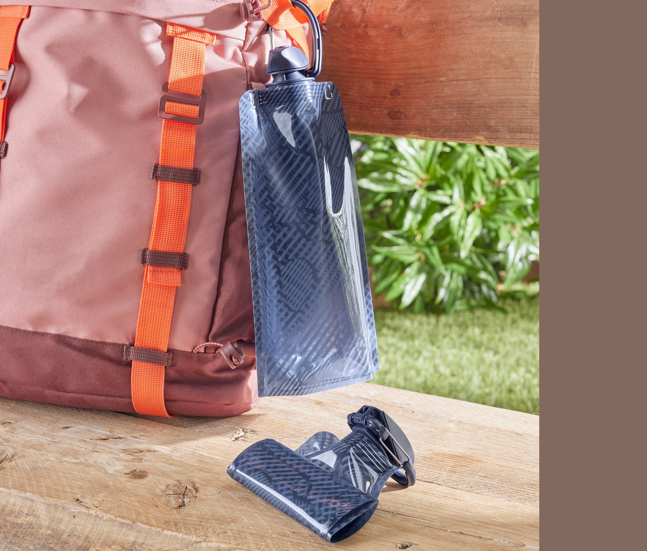 Turuncu askılı pembe-kahverengi bir sırt çantası ve 2 adet matara.