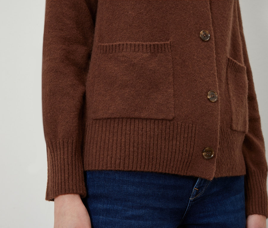 Cepleri ve düğmeleri olan kahverengi bir hırkanın yakın çekimi.