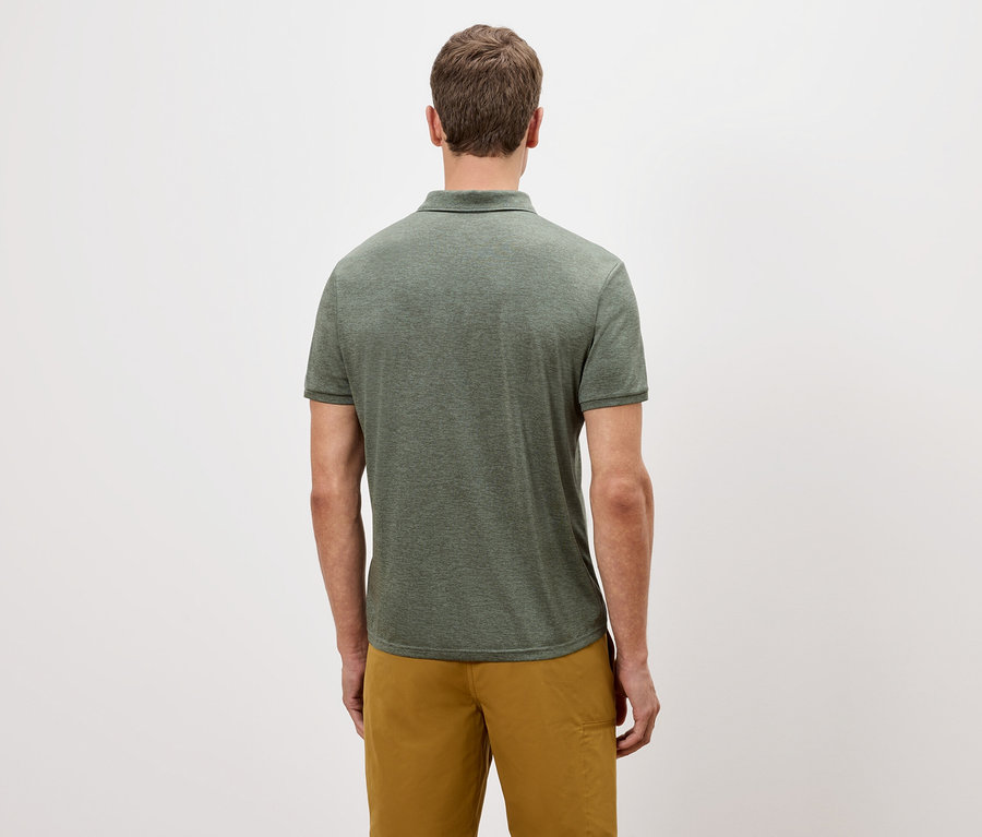 Beyaz bir arka plan önünde yeşil polo tişört ve altın rengi şort giyen bir adamın arka görünümü.