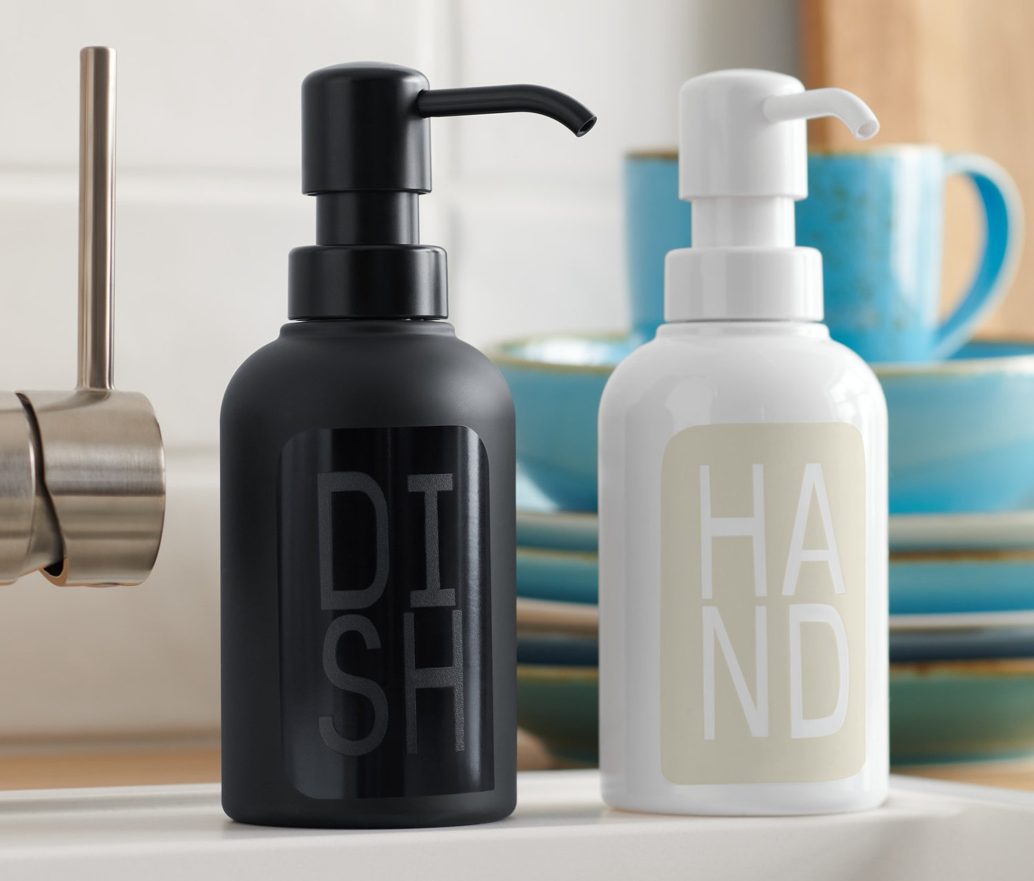 Siyah ve beyaz 2 Adet Sıvı Sabunluk lavabonun yanında duruyor.