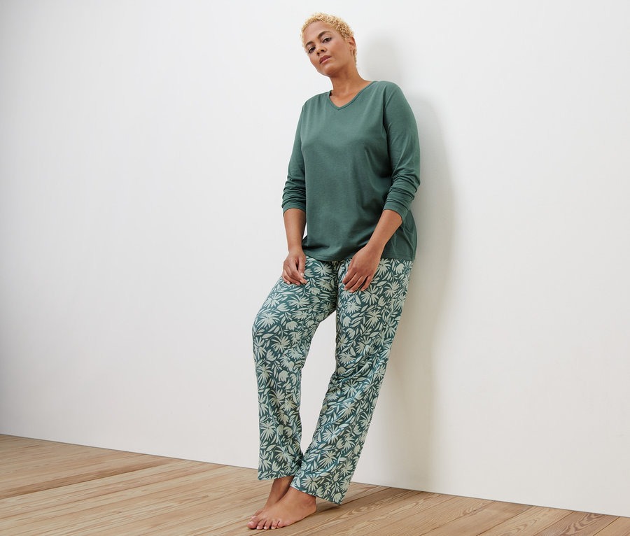 Duvara yaslanmış pijama takımı giyen kadın.