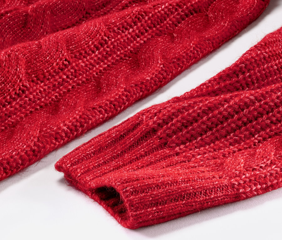 Saç örgüsü motifli, kırmızı uzun örgü kazağın yakın çekimi.