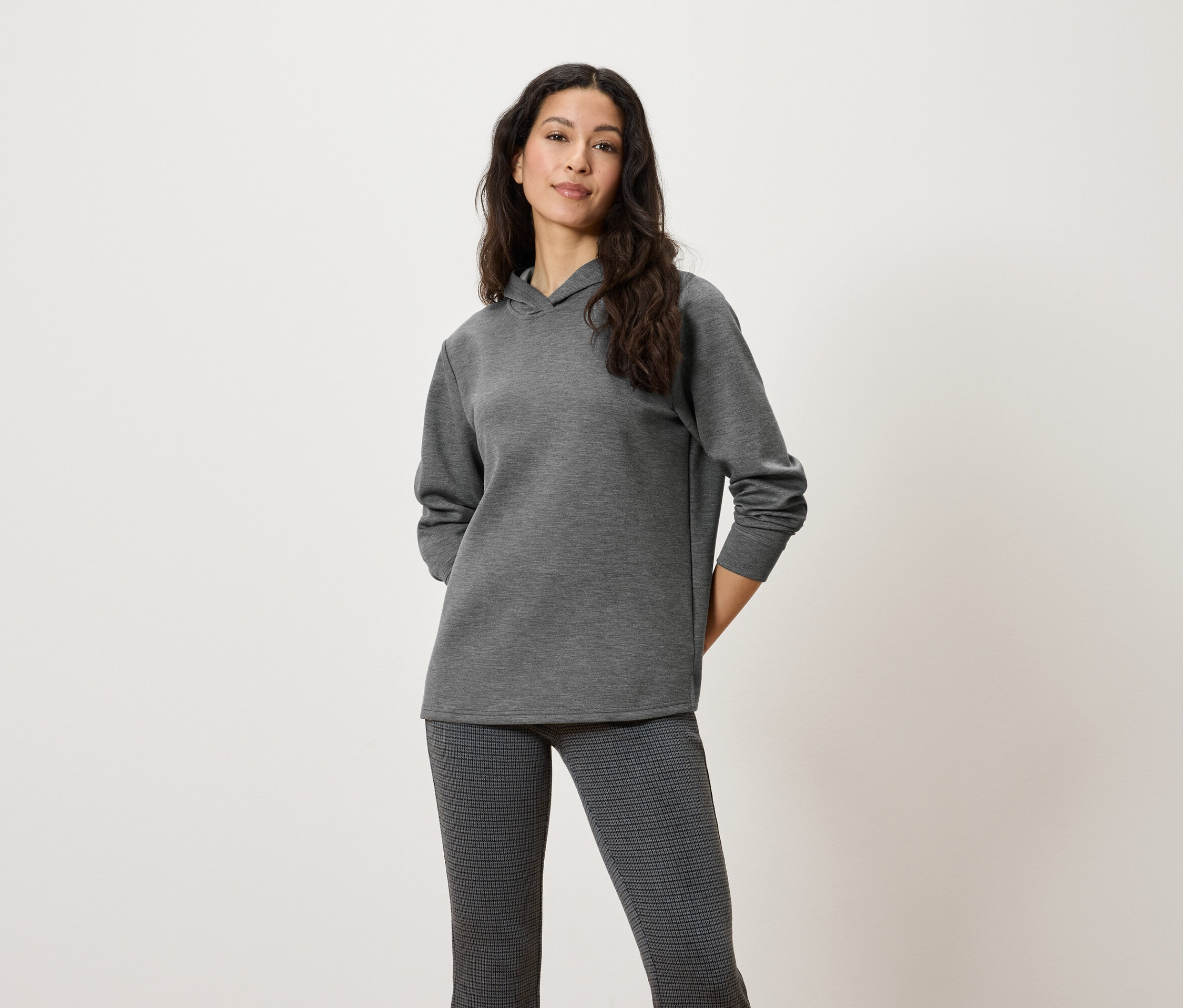 Kadın gri kapüşonlu sweatshirt ve desenli pantolonla poz veriyor.