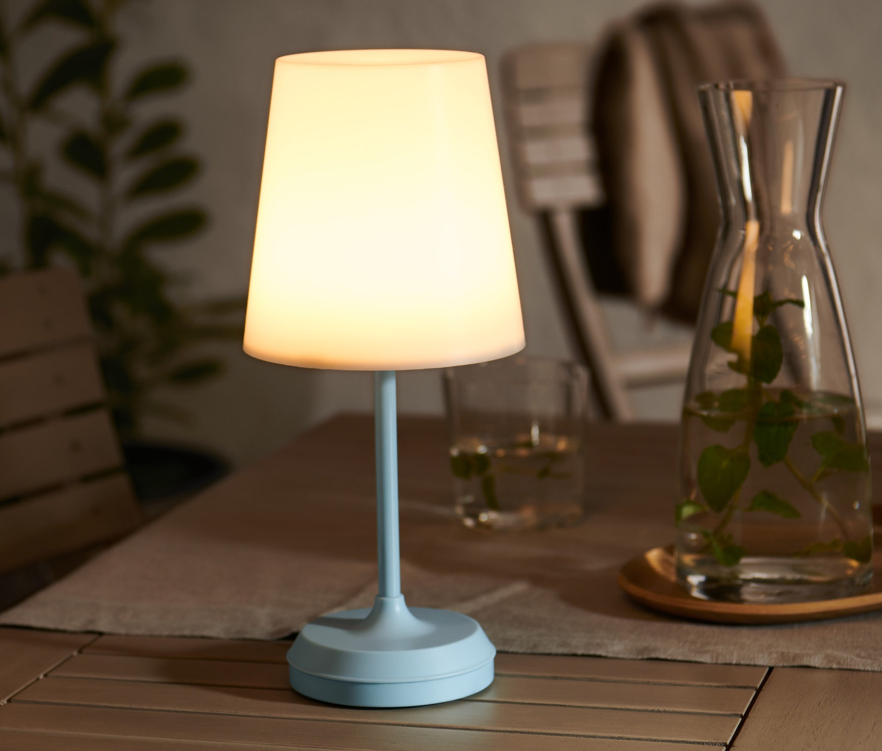 Ahşap bir masa üzerinde LED Pilli Lamba, su kabı ve bardaklar bulunmaktadır.