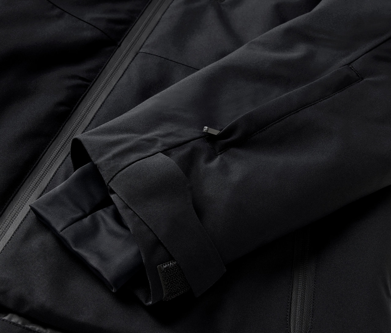 Kol ve fermuarlı cebe sahip siyah bir ceketin yakın çekimi.