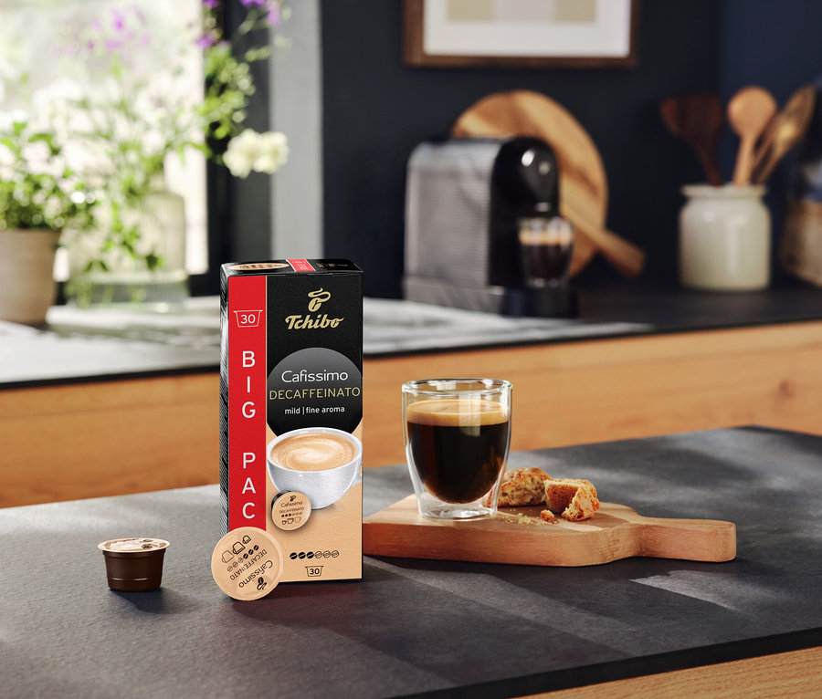 Mutfak tezgahında bir paket Cafissimo Decaffeinato kapsülü, bir fincan kahve ve bir kapsül duruyor.