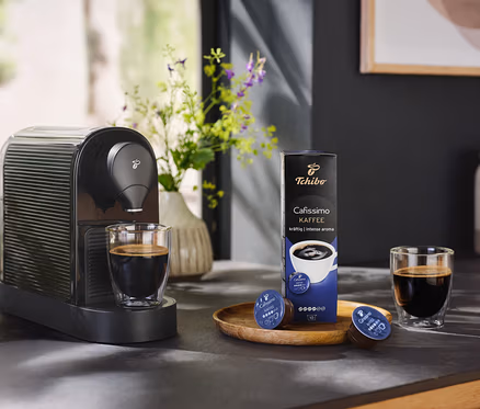 Bir fincan kahve ve bir paket kahve kapsülü ile birlikte siyah Cafissimo pure+.