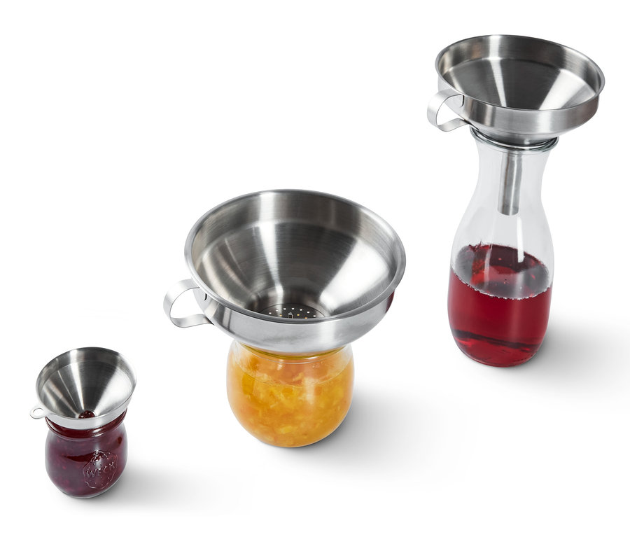 Paslanmaz çelik huniler reçel kavanozlarının üzerinde duruyor.