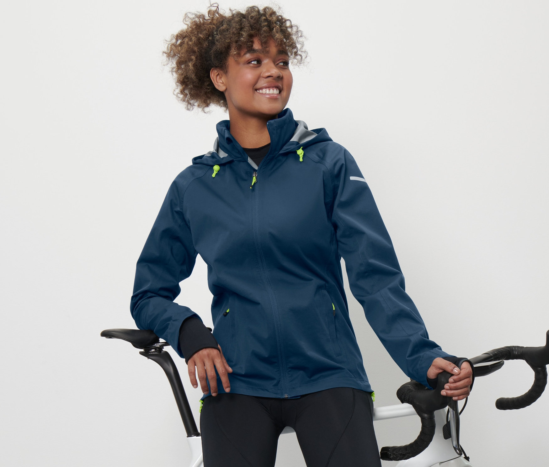 Bisikletine yaslanan bir kadın Bisiklet Yağmurluğu giyiyor.