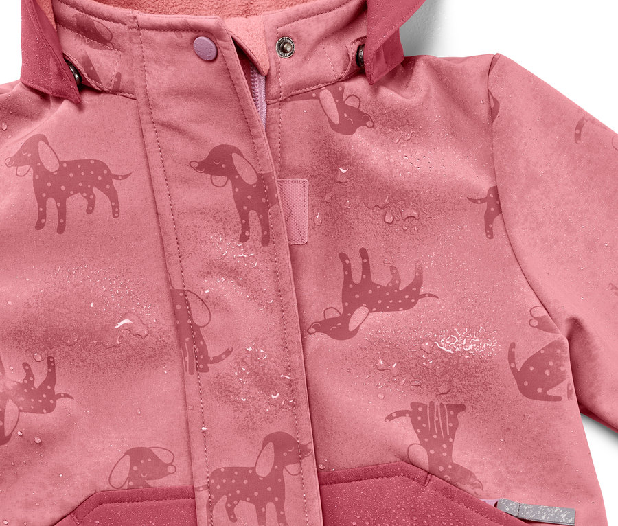 Su damlaları olan, yağmurda renk değiştiren köpek desenli pembe çocuk softshell montunun yakın çekimi.