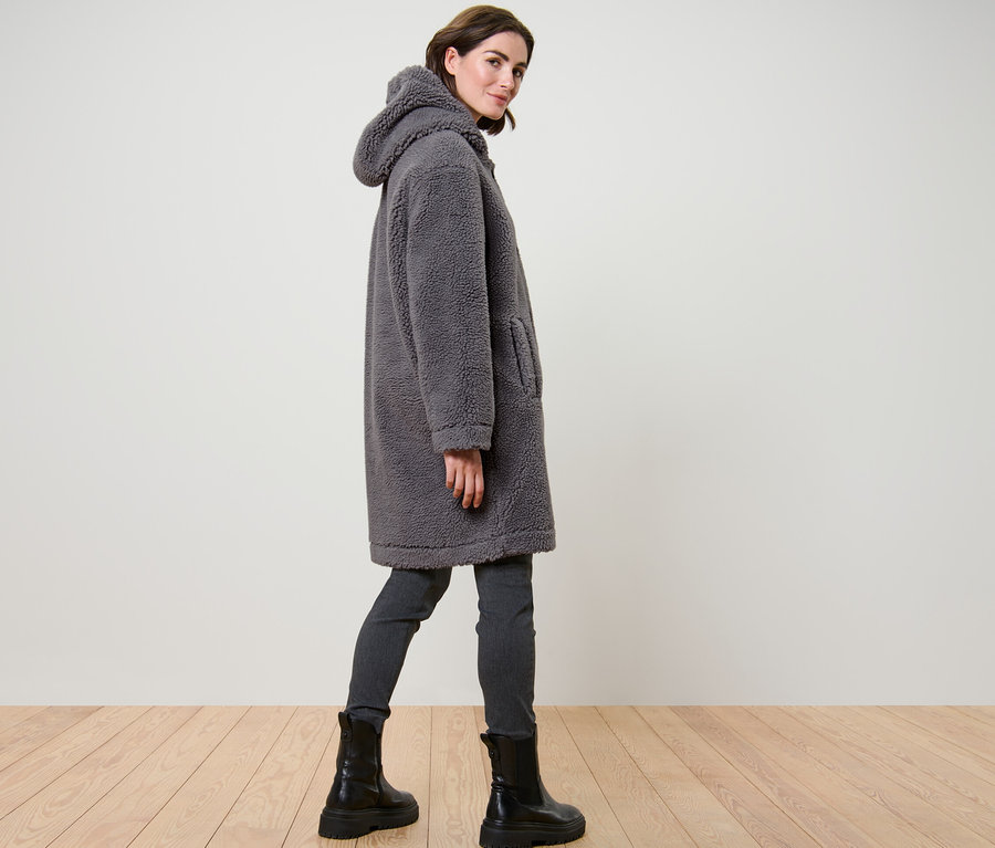 Kadın kapüşonlu gri renk teddy paltosuyla poz veriyor.