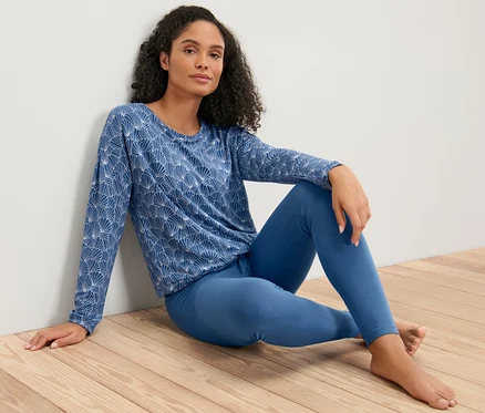 Kadın taytlı pijama takımıyla yerde oturuyor.