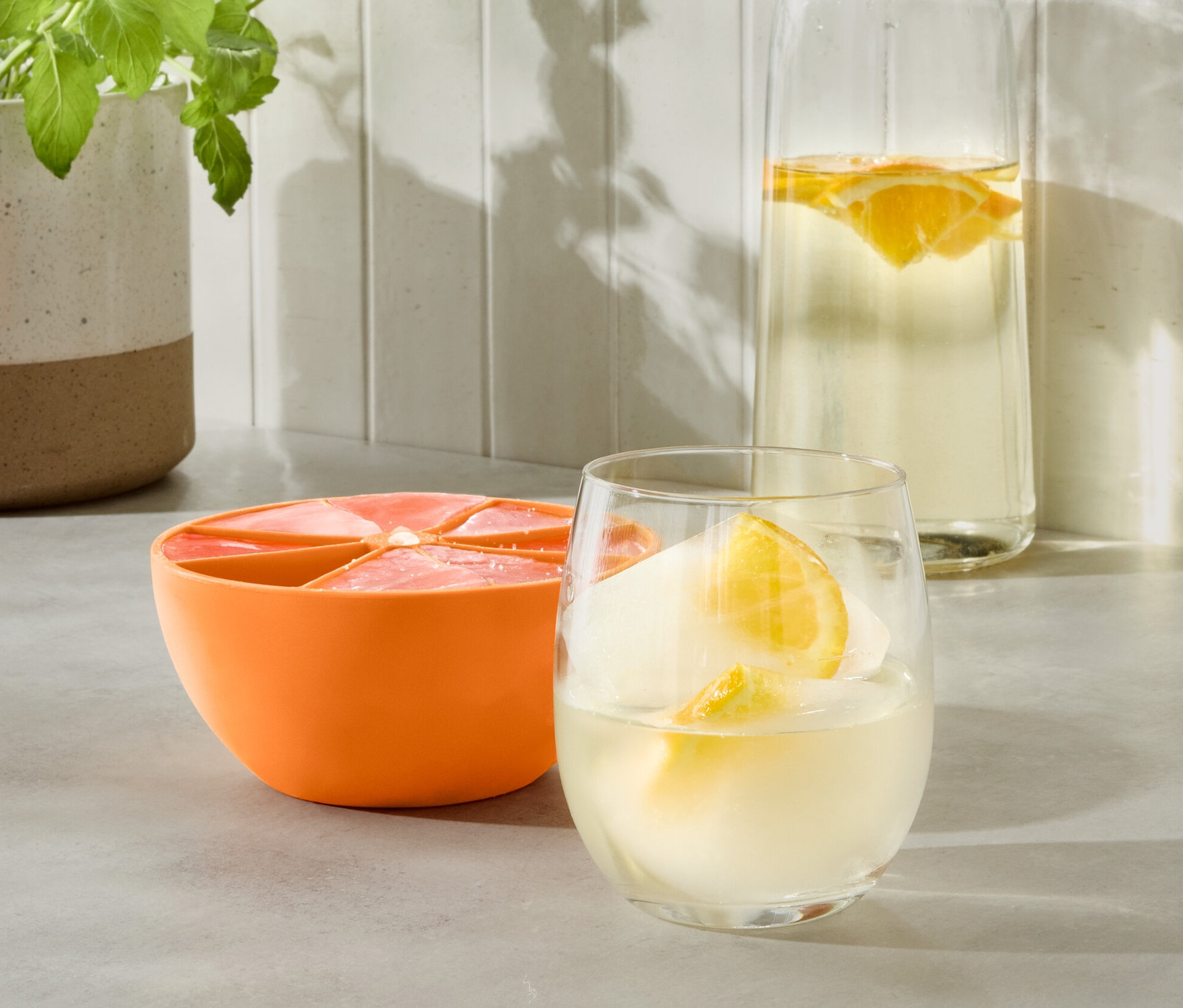İçecekli bardak ve su şişesinin yanında turuncu XL Buz Kalıbı.
