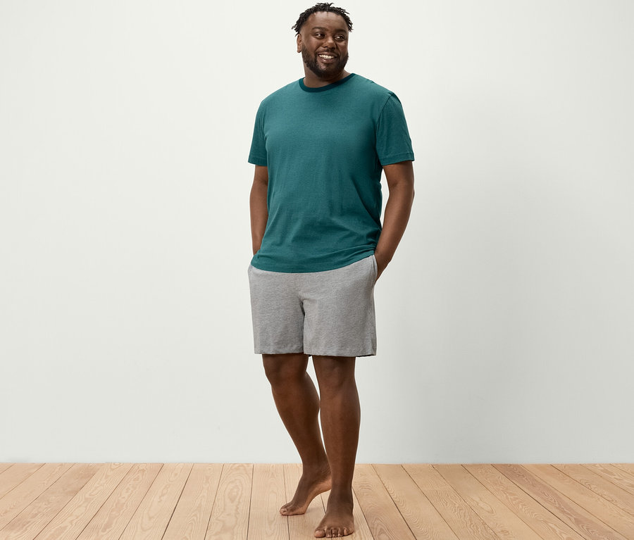 Adam şortlu pijama takımının şort ceplerinde elleriyle ayakta duruyor.