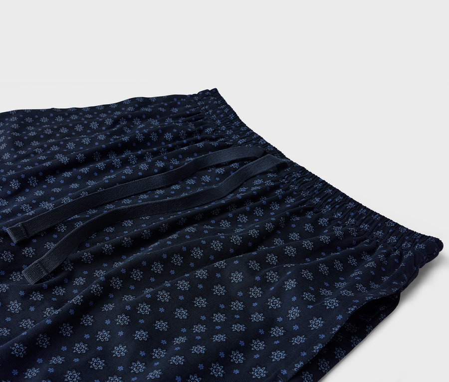 Mavi çiçek desenli ve ipli, lacivert renkli bir pijama altının yakın çekimi.