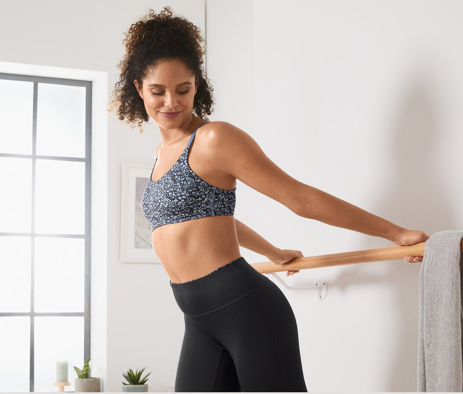 Kadın bale barında geriniyor, üzerinde Tamamı Baskılı Spor Büstiyer var.