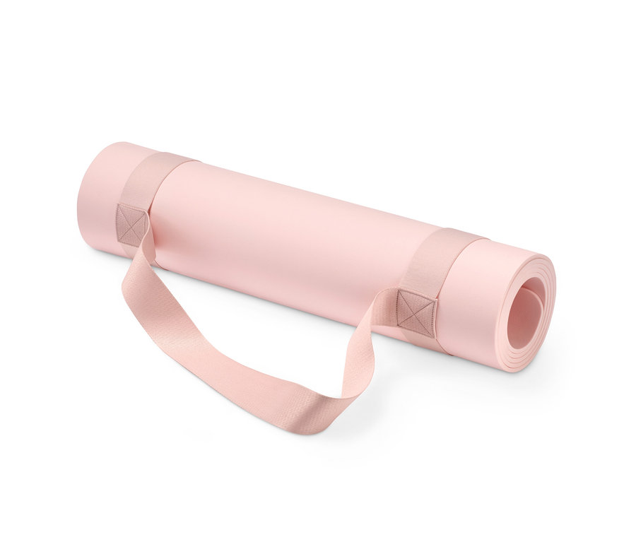 Kayışlı, rulo halinde pembe yoga ve fitness matı.