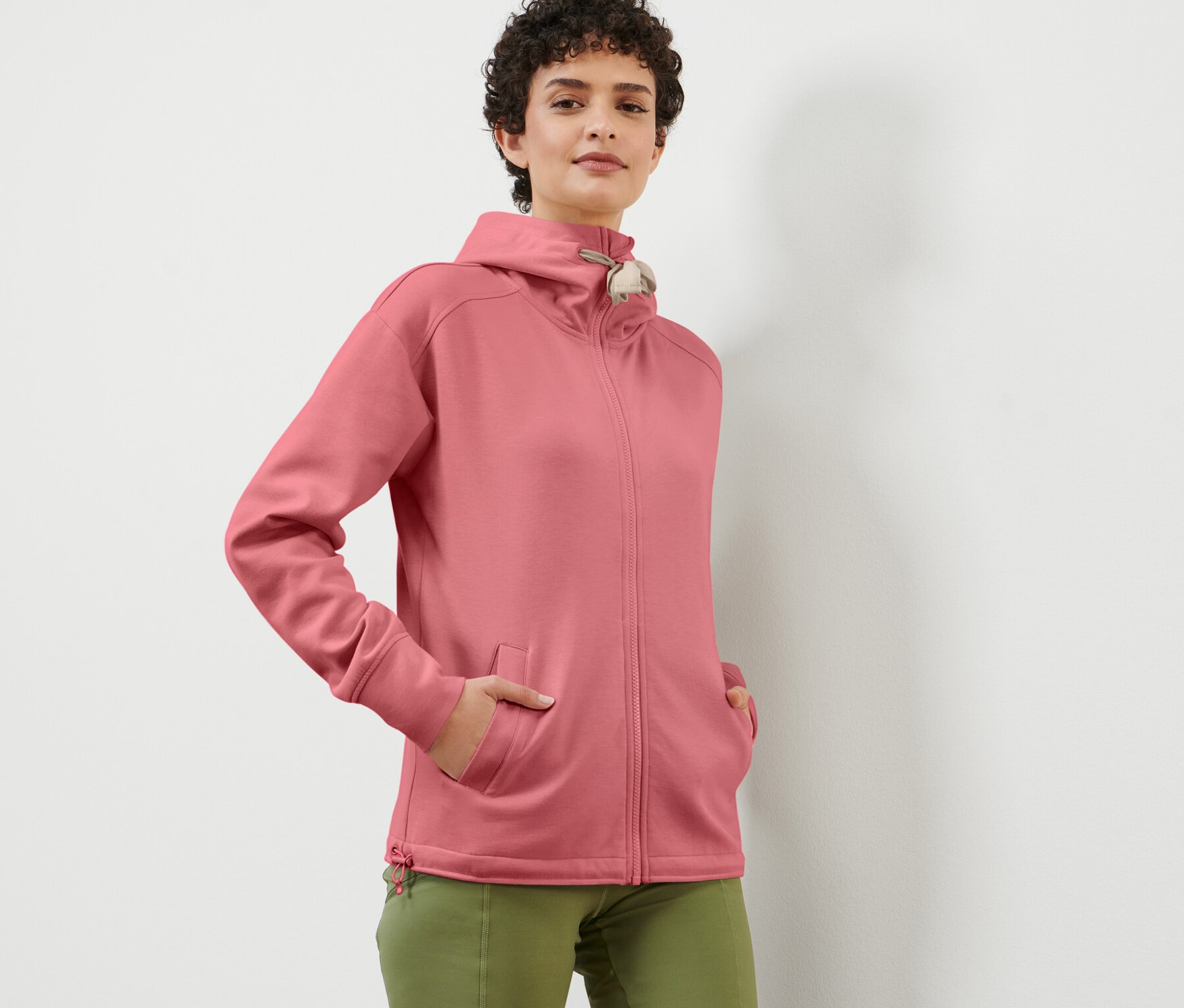 Kadın gül kurusu rengi kapüşonlu sweat ceketle poz veriyor.