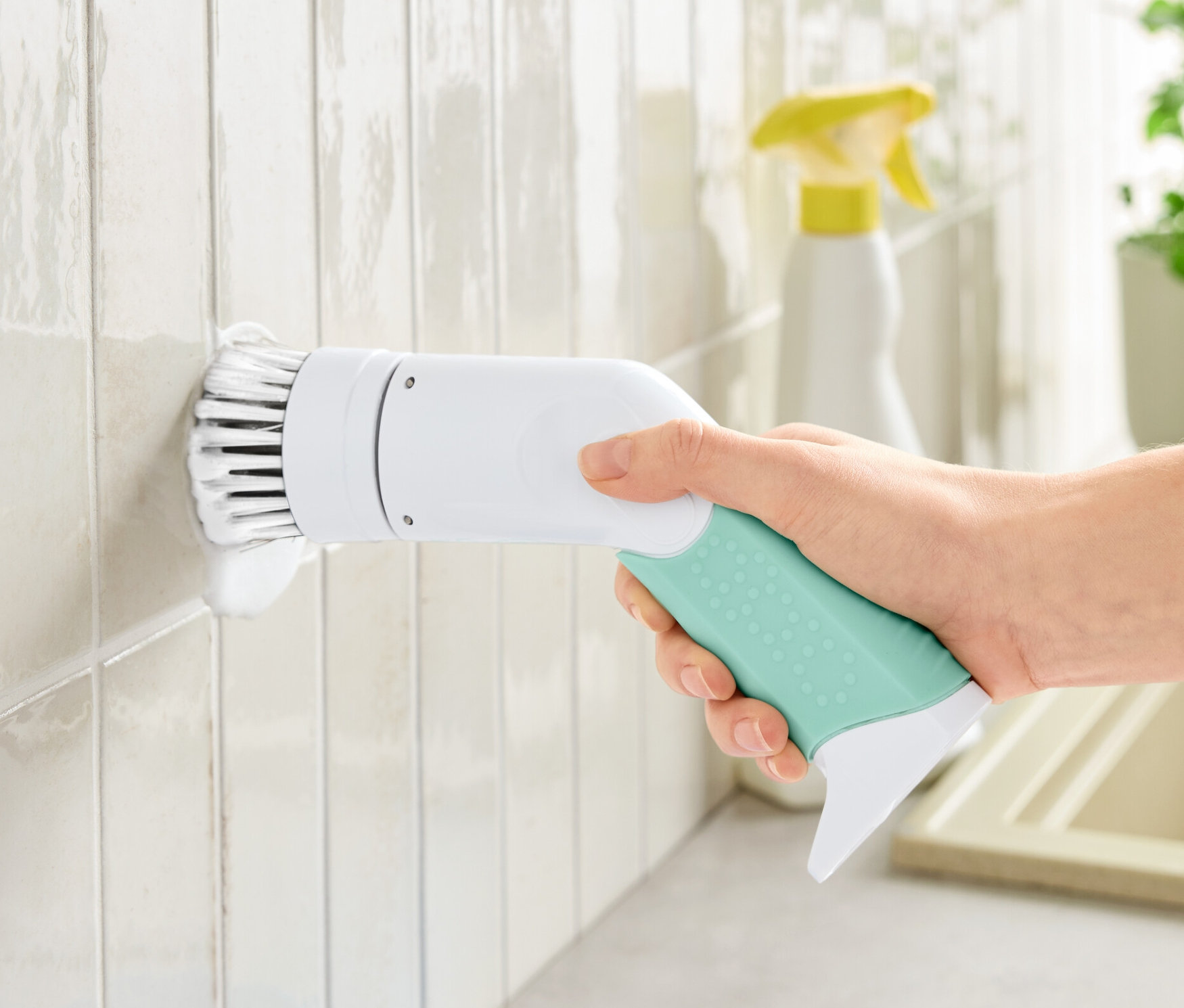 Bir el, elektrikli profesyonel bir temizleme fırçasını tutuyor ve beyaz fayansları temizliyor.